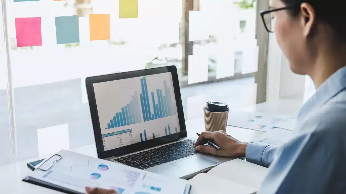 a data analyst sitting at a desk with a laptop and pen in front of them