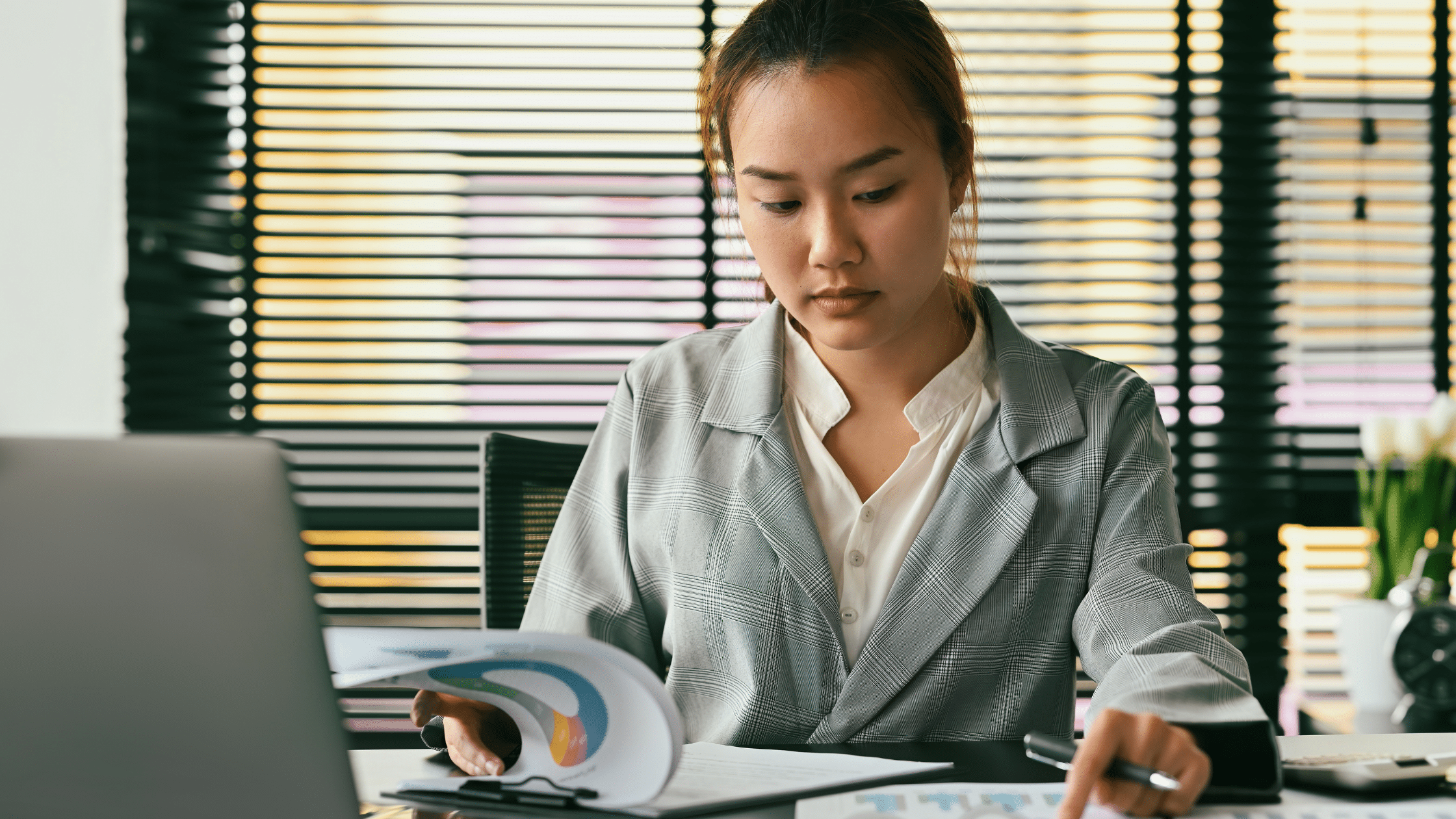 an image of a woman as cybersecurity analyst looking at a laptop and graphs for it infrastructure