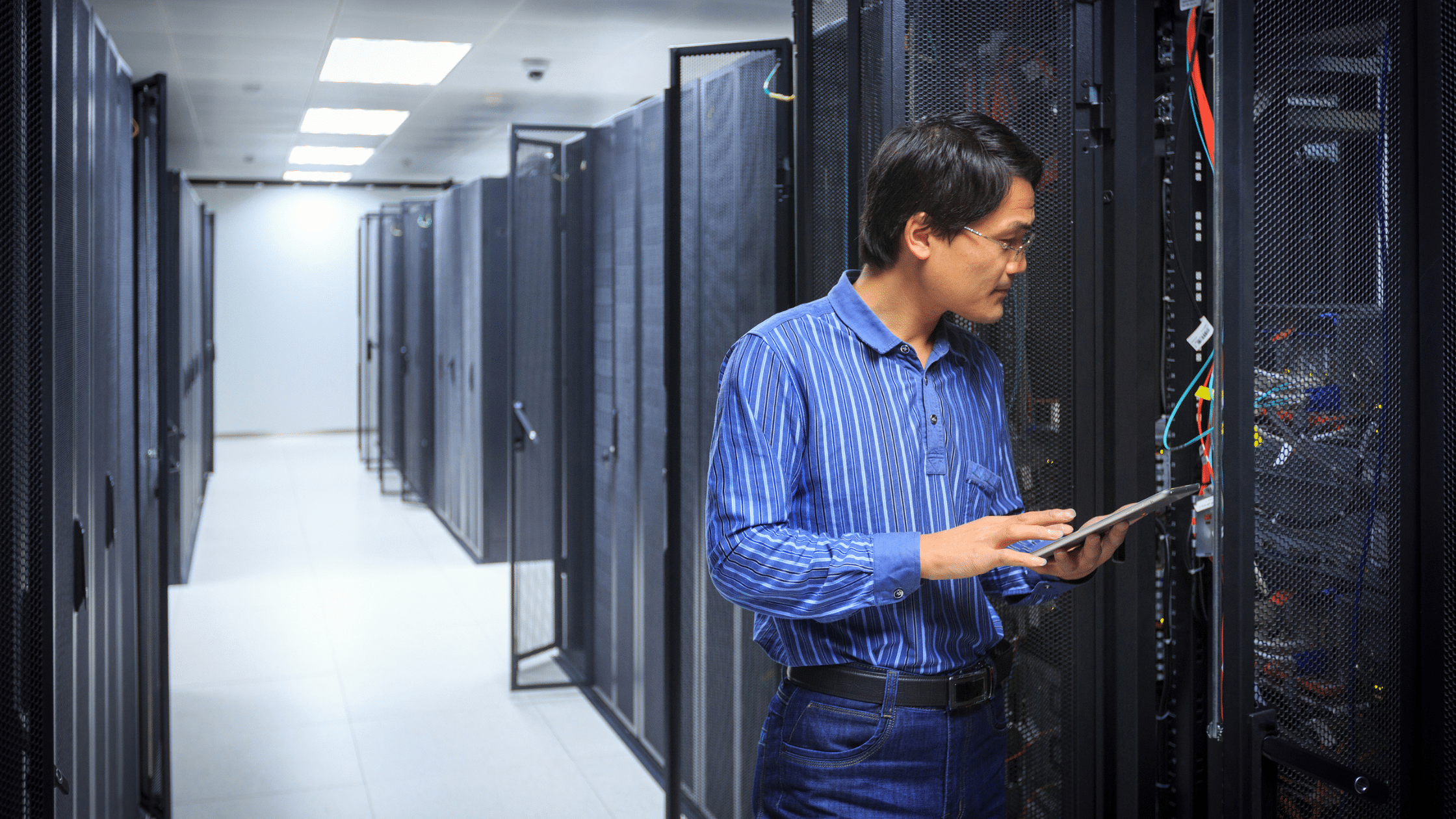 an image of a man as a network administrator looking at servers in IT infrastructure