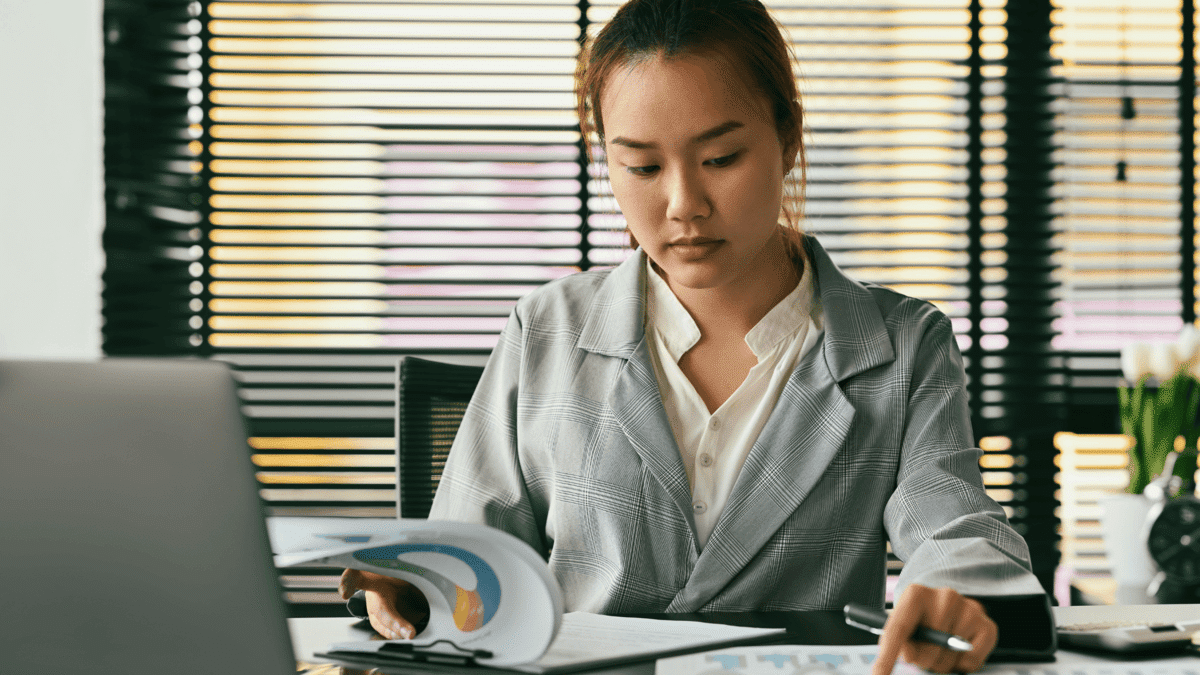 an image of a woman as cybersecurity analyst looking at a laptop and graphs for it infrastructure