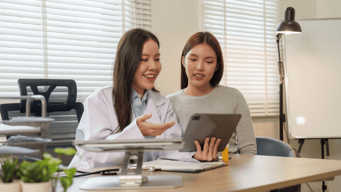 Healthcare professional reviewing information on a tablet with a patient