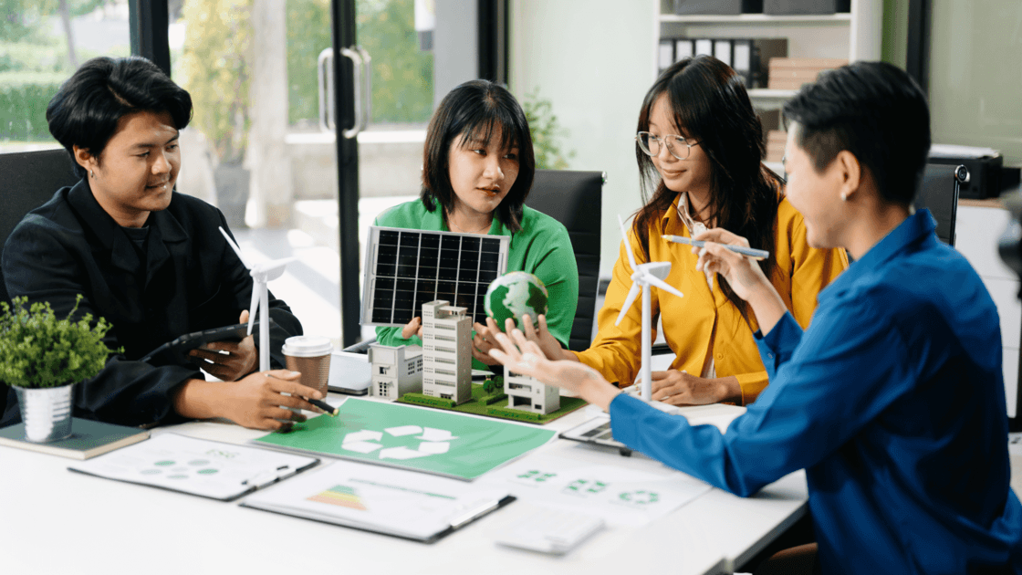 Team discussing sustainability, ESG and green economy plans around a table with plants